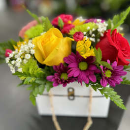 Colorful bouquet of roses and daisies in a white gift box