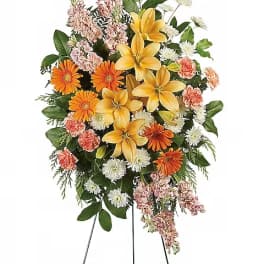 Standing floral spray with yellow lilies, orange daisies, and pink carnations
