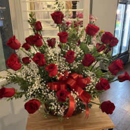 Basket arrangement of red roses with baby's breath and a red ribbon