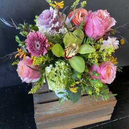 Pink roses and mixed blooms in a wooden box arrangement