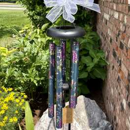 Black wind chime with a white bow hanging outdoors
