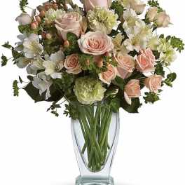 Bouquet of pale pink roses and white flowers in a clear glass vase