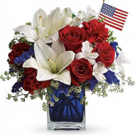 Red roses and white lilies in a blue glass vase with a small American flag