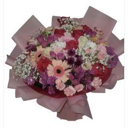 Mixed bouquet of pink, purple, and white flowers wrapped in pink paper