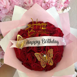 Bouquet of red roses wrapped in pink paper with a birthday ribbon