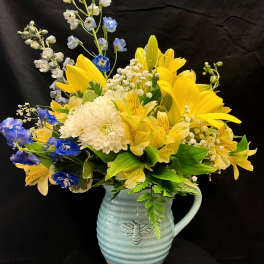 Yellow and blue mixed bouquet in a light blue ceramic pitcher
