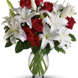 Red roses and white lilies arranged in a clear glass vase