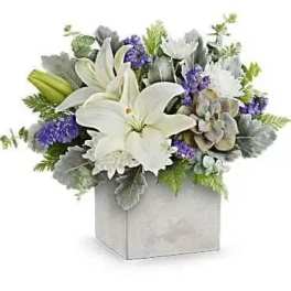 White lilies and purple flowers arranged in a square box