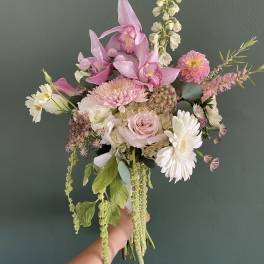 Handheld bouquet of pink orchids, roses, and white daisies