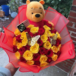 Bouquet of red and yellow roses with a Winnie the Pooh plush