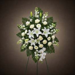 White floral standing spray with lilies and roses on an easel