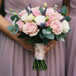Handheld bouquet of pink and white roses with purple accents