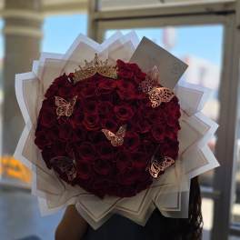 Large bouquet of deep red roses with a gold crown and butterfly decorations