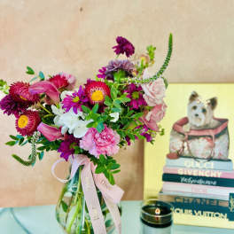 Mixed pink and purple bouquet in a glass vase with a ribbon