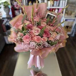 Pink rose bouquet with carnations and tall buds in pastel wrapping