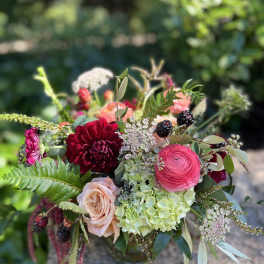 Bouquet of red, pink, and peach flowers with berries in a vase