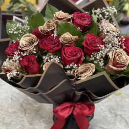 Bouquet of red and gold roses wrapped in black paper with a red ribbon