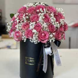Pink roses arranged in a black hatbox with white baby's breath