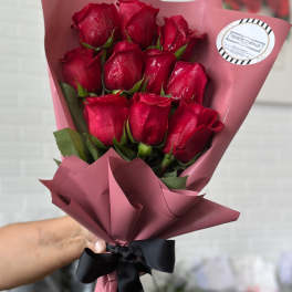 Bouquet of red roses wrapped in pink paper with a black ribbon