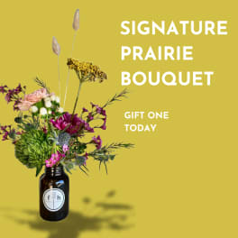 Two small floral arrangements in brown bottles on a wood stump