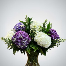 Purple and white hydrangea arrangement in a glass vase