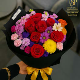Bouquet of red roses and mixed colorful flowers wrapped in black paper