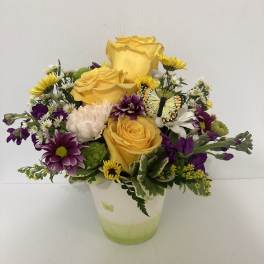 Yellow roses and purple daisies in a white vase with a butterfly accent