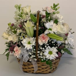 Basket arrangement of white flowers with pink accents and a ribbon bow