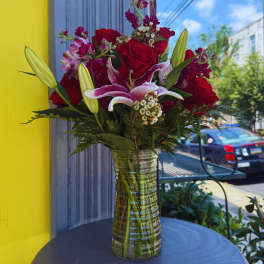Bouquet of red roses and pink lilies in a clear glass vase