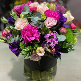 Bouquet of pink, purple, and white flowers in a black box with ribbon