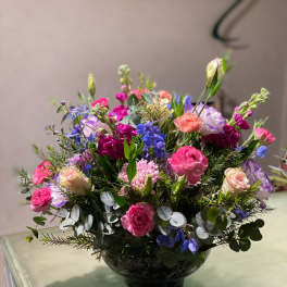 Mixed pink, purple, and blue flowers arranged in a black vase