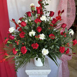 Tall red and white floral arrangement in a white pot