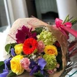Bouquet of mixed colorful flowers wrapped in paper with a pink ribbon