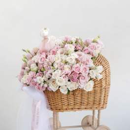 Pink and white rose bouquet in a wicker baby carriage with a small doll topper