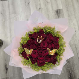 Bouquet of deep red roses with pink wrapping and butterfly picks