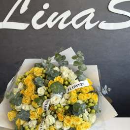 Bouquet of yellow and white roses with eucalyptus and berry accents