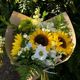 Bouquet of sunflowers, white daisies, and green chrysanthemums wrapped in brown paper
