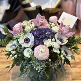 Round bouquet with pink orchids, white anemones, and purple hydrangea in a vase