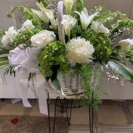 White lilies and chrysanthemums in a white basket with a ribbon