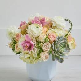 Pastel bouquet of roses, ranunculus, and orchids in a white vase