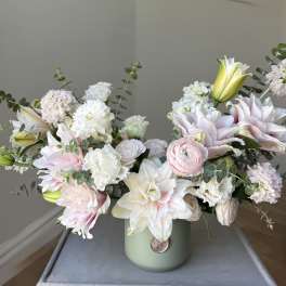Pastel bouquet of lilies, carnations, and ranunculus in a green vase