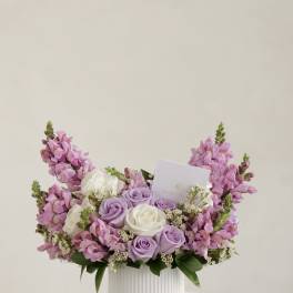 Pink and lavender roses arranged in a white ribbed vase