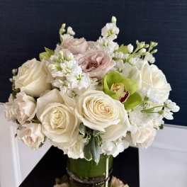 Cream roses and white flowers arranged in a glass vase