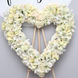 Heart-shaped white floral wreath on a wooden easel