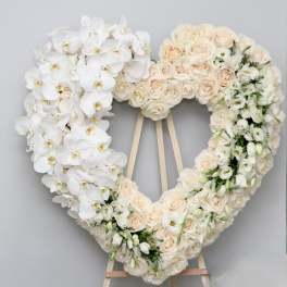 Heart-shaped floral wreath with white orchids and blush roses on an easel