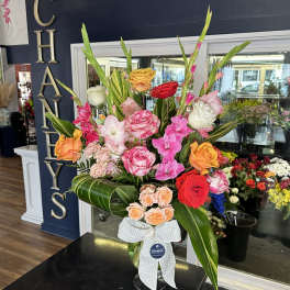 Tall mixed bouquet of pink, red, orange, and white roses in a glass vase