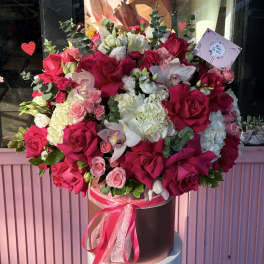 Large bouquet of pink and white roses with orchids in a hatbox