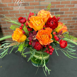 Orange and red floral arrangement in a glass vase