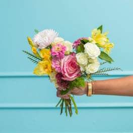 Handheld bouquet of pink, white, and yellow flowers