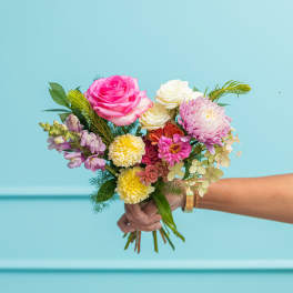 Handheld bouquet of pink and white flowers with mixed blooms